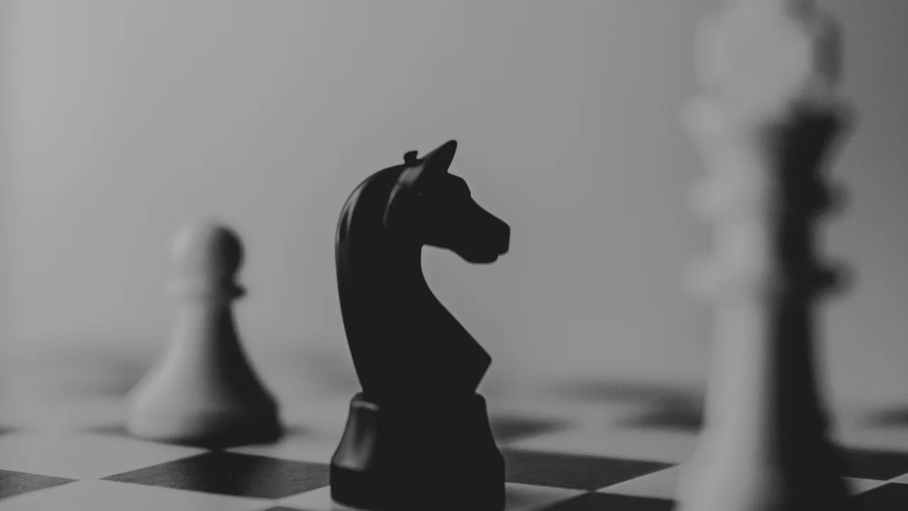 Black chess knight in sharp focus on a board with blurred pieces in the background, representing strategic judgment in an era of cheap execution
